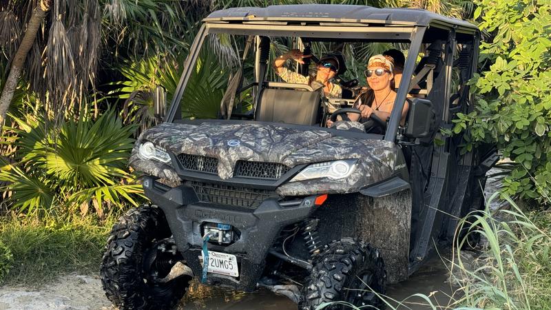 Guests driving a 4x4 buggy through a jungle trail and a water crossing in Cozumel